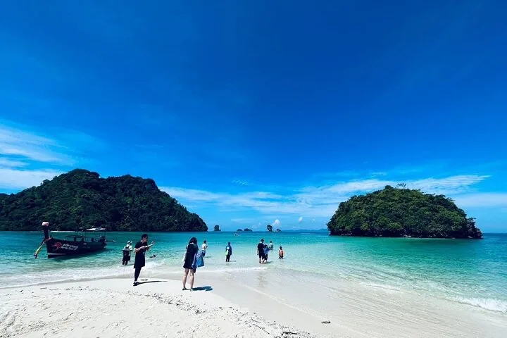 Touristen, die auf einer wunderschönen Sandbank laufen, die sich zu üppigen Inseln erstreckt.
