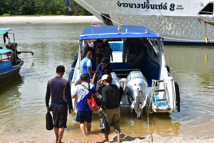 Passagiere, die von einem Sandstrand aus ein Speedboot von Sea Eagle Tour besteigen.