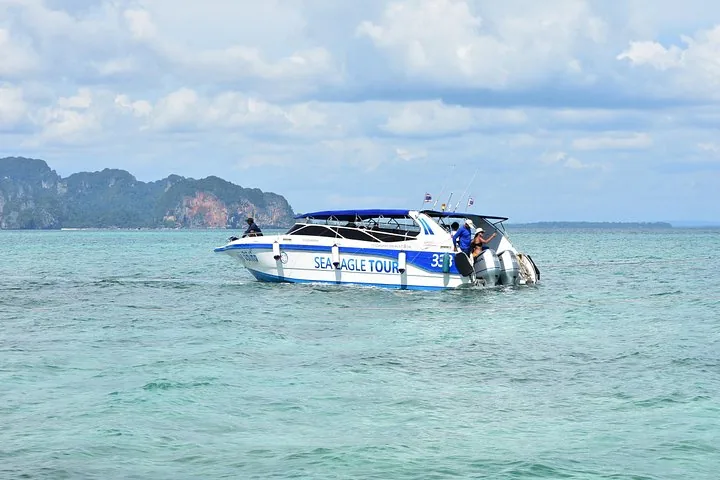 Ein Speedboot von Sea Eagle Tour, das auf klarem blauem Wasser in der Nähe felsiger Inseln dahingleitet.